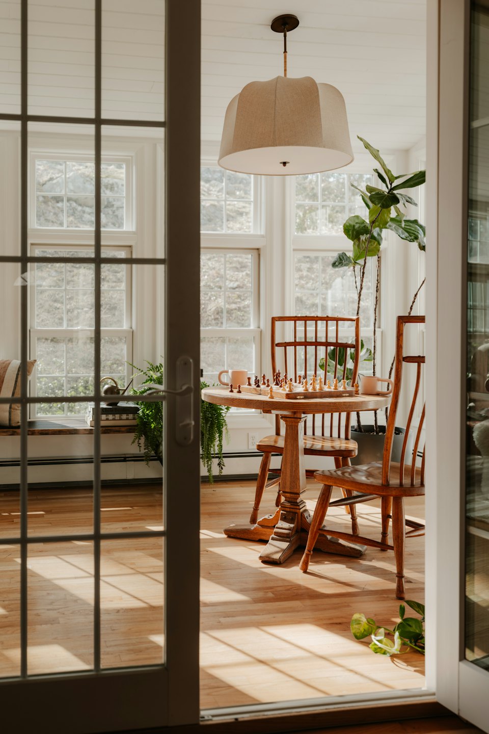 Zonnige kamer met ronde tafel en schaakspel klaargezet voor een partij.