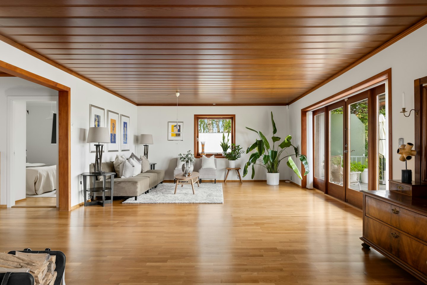 Lichte woonkamer met houten vloeren en groene planten.